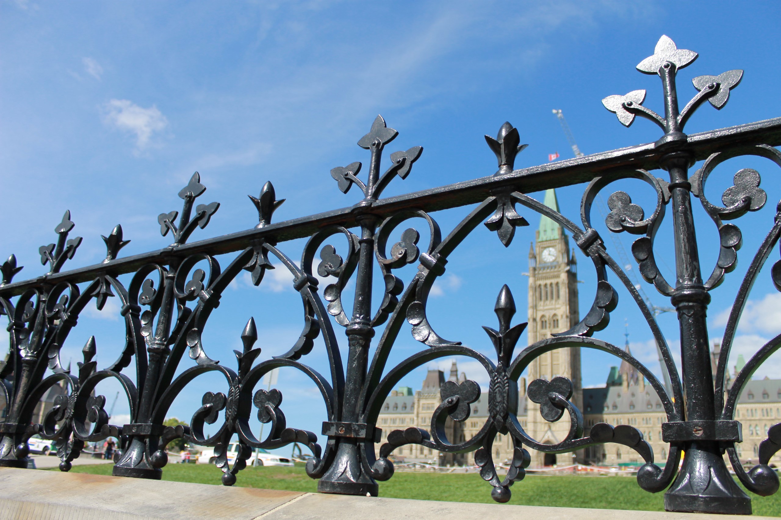 The exterior gates of Centre Block in the foreground, with the Peace Tower visible behind the fence in the background.